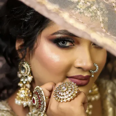 A perfect example of a modern bridal look, featuring a soft smokey eye, matte lips, and statement kundan jewelry. This close-up highlights the flawless base and intricate details we teach.