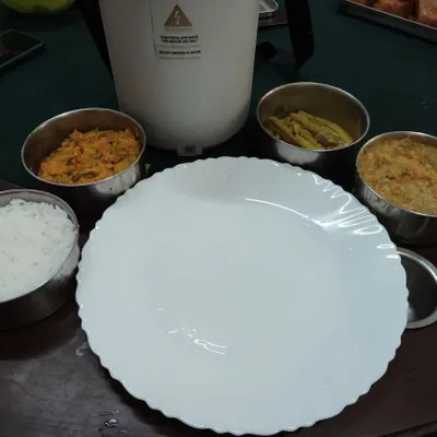 This is my homestyle vegetarian lunch parcel, prepared with less oil and balanced spices, just like a mother would make. It includes steamed rice, dal, a vegetable curry, and a side dish, all packed fresh for you.