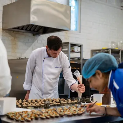 Here is Chef Maxime Montay leading his team in the kitchen. This behind-the-scenes shot shows the focus and collaboration that goes into preparing for a large event.