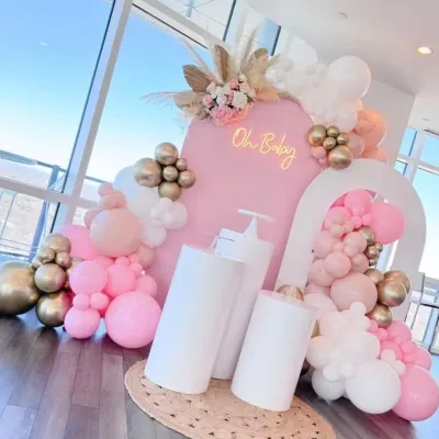 A chic and modern baby shower setup with a pink arched backdrop, an 'Oh Baby' neon sign, and a beautiful balloon arrangement in pink, white, and gold. The pampas grass and floral accents add a touch of boho elegance.