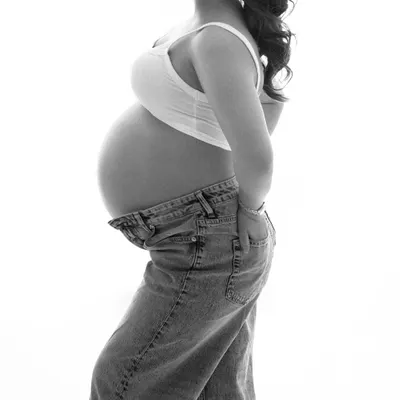 A simple and powerful black and white profile shot. This minimalist portrait beautifully highlights the silhouette of the baby bump, creating a classic and artistic image.