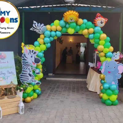 A grand balloon archway welcomes guests to a jungle-themed party. Character cutouts of a zebra and elephant stand at the entrance, setting the stage for the wild adventure inside.