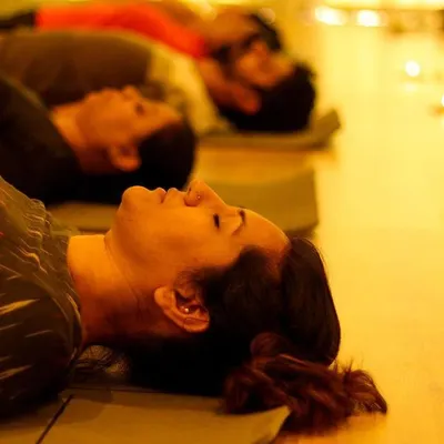 In the warm glow of candlelight, participants rest in Savasana during a sound bath. This state of deep relaxation allows the healing frequencies of the instruments to resonate fully through the body and mind.