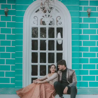 A romantic moment on the steps of a building with a beautiful turquoise brick wall. The bride's flowing gown and the elegant setting create a modern fairytale look.