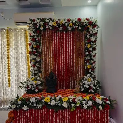 This is a beautiful floral setup for a home pooja or deity installation. I created a frame of fresh flowers around a red backdrop, with a decorated platform for the idol.