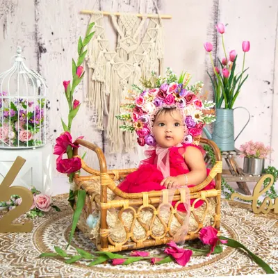 Celebrating six months with a beautiful half-birthday floral setup. The '1/2' sign, rustic basket, and a stunning flower bonnet make this a memorable sitter session.