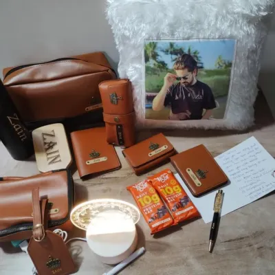 This personalized men's gift set includes a variety of tan leather accessories like a wallet, pouch, and luggage tag, all customized with a name and a crown charm. It also features a custom photo pillow.