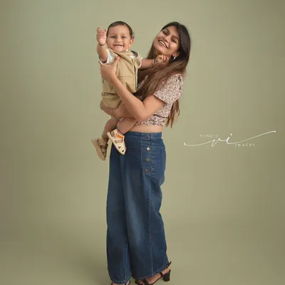 A mother's love and a baby's happy wave. This studio portrait captures a fun and loving moment between a mom and her son against a clean, simple backdrop.