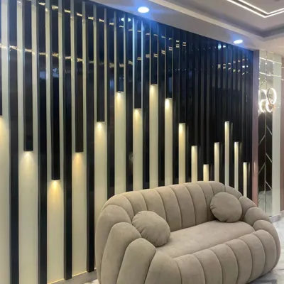 This partition wall uses vertical black slats with integrated, staggered lighting. It acts as a stunning backdrop for the modern sofa while also subtly dividing the space.
