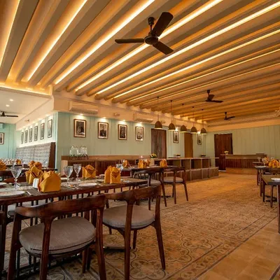 The colonial-themed interior we designed for Ebony Restaurant in Whitefield, featuring a coffered ceiling with cove lighting, elegant seating, and warm wood tones.