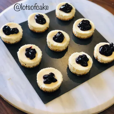 An aerial view of my mini blueberry cheesecakes arranged on a platter. Each one is a perfect, creamy bite with a dollop of blueberry topping.