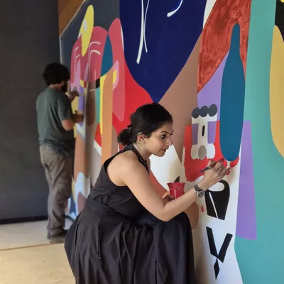 The artist at work, adding details to a large, colorful Picasso-inspired mural. This is where the vision starts to take tangible form.