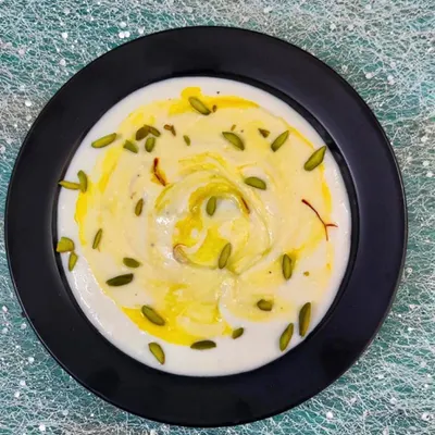 A bowl of our creamy, homemade Shrikhand, garnished with saffron and pistachios. This sweet and tangy dessert is made from strained yogurt and is a perfect end to any meal, especially when paired with hot puris.