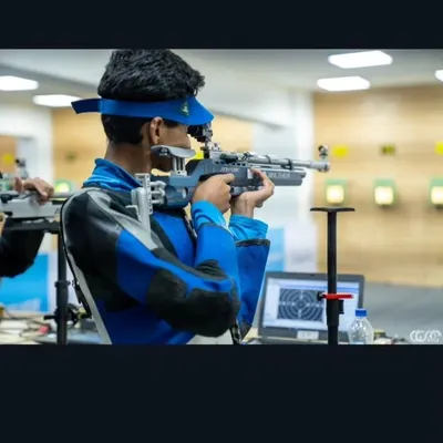 A close-up of a rifle shooter in the zone, demonstrating the intense focus required for precision shooting. The laptop shows the use of SCATT analysis to perfect technique.