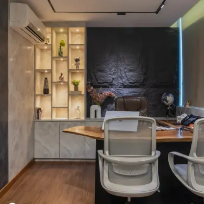 A shot of the executive cabin we designed, featuring a solid wood desk, a textured stone accent wall, and integrated shelving with magnetic track lights.