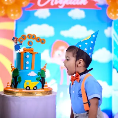 The moment of pure wonder right before the smash! This little one, dressed in a Blippi-inspired outfit, is amazed by his colorful birthday cake during his party.