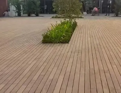We specialize in large-scale decking projects. This expansive wooden deck creates a clean, uniform surface, with cutouts for trees and plants to integrate nature into the design.