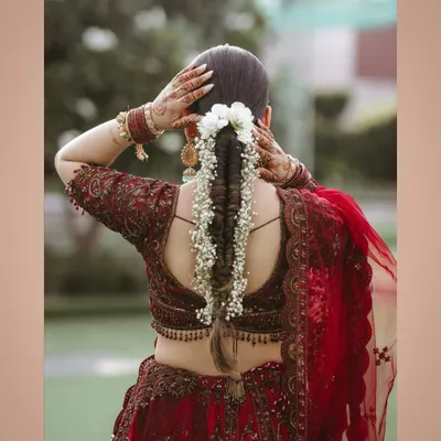 A beautiful shot focusing on the bride's intricate hairstyle with fresh flowers and her elegant blouse design.