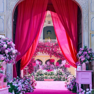 This is how we do royal entrances. A vibrant gulabi carpet and lush floral arrangements guide guests through majestic palace arches, framed by dramatic fuchsia drapes. It’s a welcome that promises the grandeur to come.