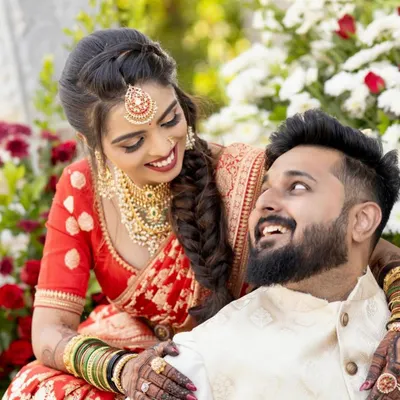 A candid moment of joy between the bride and groom. Her deep red saree and gold jewelry are beautifully accented by the rich color of her full-hand bridal mehendi.