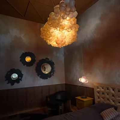 A breathtaking installation of the Bocci 100 series in a moody, intimate bedroom. The fixture hangs like a cluster of captured light, demonstrating how a single, powerful piece can define the character of a room.