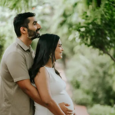 An outdoor maternity portrait for a couple, framed by lush greenery. This session focuses on capturing the shared anticipation and quiet love before the baby arrives.