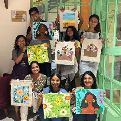 A group of happy artists showing off their custom-painted tote bags. From floral designs to abstract portraits, each bag is a unique expression of their creativity.