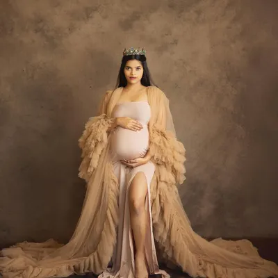 A portrait of pure royalty. Wearing a crown and a beautiful nude gown, this mom-to-be looks absolutely regal, capturing the powerful essence of motherhood in a fine art studio setting.