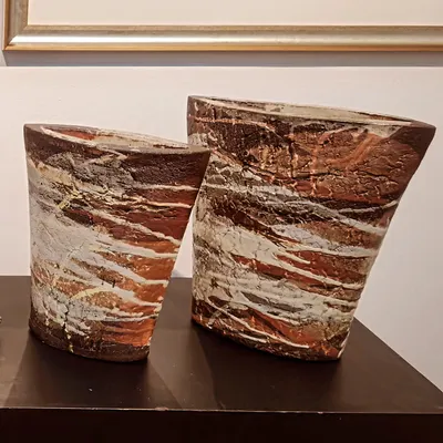 A pair of hand-built sculptural vases with a heavily textured, layered surface that mimics natural rock formations. These pieces are designed to be artistic focal points in any room.