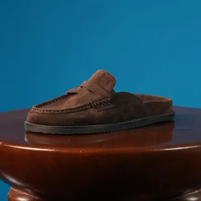 The Suede Alba mule in Umber, presented as part of a coordinated ensemble. This rich brown suede clog is the epitome of relaxed sophistication, designed to be your most comfortable and stylish everyday shoe.