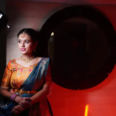 An artistic shot of Yoshitha, with dramatic red lighting highlighting her beautiful features and colorful lehenga.