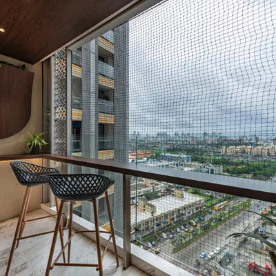 Tranquil elegance awaits on this balcony. With a bar-height counter and chic chairs, it's a serene retreat under open skies, offering a perfect spot to unwind and take in the city view.