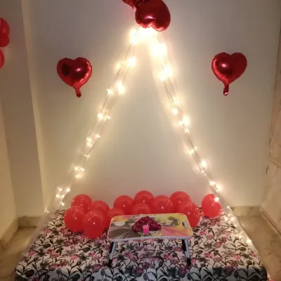 A great example of my simple and affordable cabana decor. This setup for a sixth-month anniversary uses a floor mattress, a fairy light canopy, and red heart-shaped foil balloons for a classic romantic look.