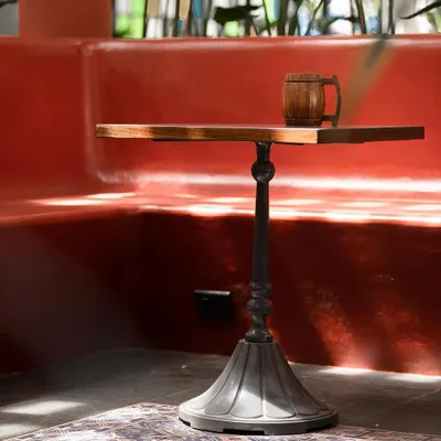 A custom-designed cast iron table base paired with a solid wood top, set against a red-oxide finished booth. We collaborate with skilled vendors like Loyora Spaces to create bespoke furniture that elevates the spaces we design.