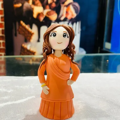 A close-up of a custom-made fondant figurine of a woman in a beautiful orange traditional dress. I can create personalized toppers to match the birthday person's likeness and outfit.