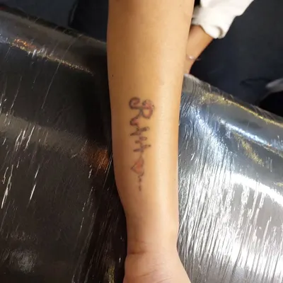 This 'Ritu' name tattoo has been significantly faded through laser sessions. It is now light enough to be easily concealed with a new, vibrant cover-up tattoo.