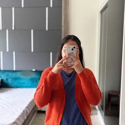 For a pop of color, here is our basic knitted cardigan in a warm orange. It's an affordable and comfortable option for everyday layering, designed to fit sizes S, M, and L.
