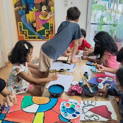 Our studio buzzing with creative energy during a painting class. The space is set up with large tables that allow for collaborative and individual work, with plenty of room for kids to spread out and create.