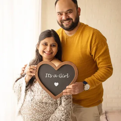 A happy couple announcing "It's a Girl" with a heart-shaped chalkboard sign. A simple and sweet way to share your exciting news.