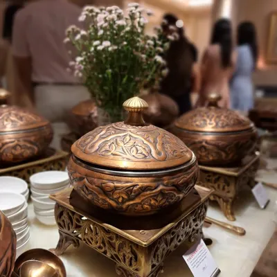 Our signature Mughlai dinner setup, featuring intricately carved copper and brass serving dishes. This presentation style is essential to the authentic, high-end Indian dining experience we provide for weddings and special occasions.
