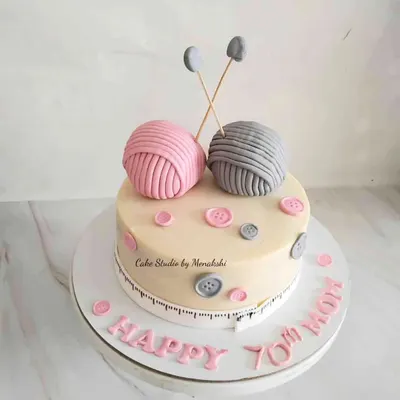 A sweet knitting-themed cake to celebrate a mom's 70th birthday. The design features edible balls of yarn, knitting needles, and buttons, all handcrafted with minimal fondant.