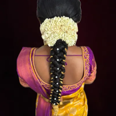 A classic South Indian bridal braid, beautifully decorated with fresh jasmine flowers and delicate pearl accessories. This hairstyle is timeless and photographs wonderfully.