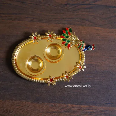 A beautiful gold-plated tray with a peacock design and two holders for kumkum and haldi, adorned with colorful meenakari work.