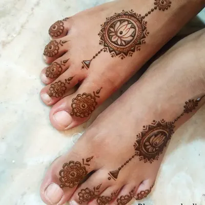 A simple and elegant foot design featuring a central lotus mandala connected to the toes with a delicate chain. This minimalist style is perfect for any occasion, adding a touch of grace and beauty.