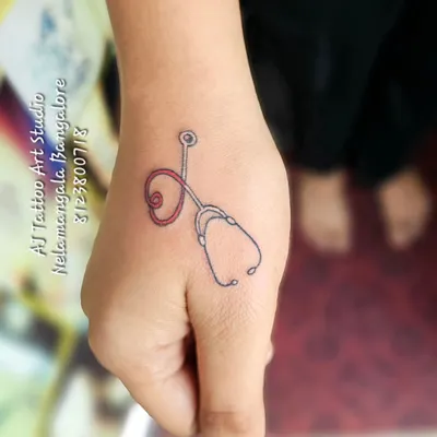 A tiny stethoscope tattoo on the thumb, a perfect design for a doctor or medical professional.