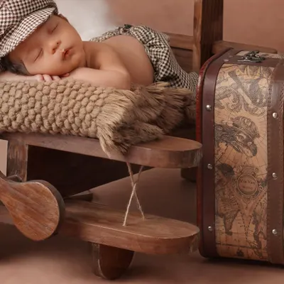 And the adventure begins. This newborn photography theme features a tiny pilot snoozing on a wooden airplane, ready to fly into his dreams. I use props like vintage-style suitcases to build a complete story.