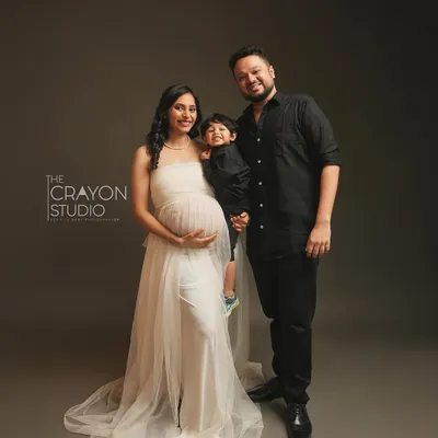 A beautiful portrait of a family on the cusp of a new chapter. The mother's serene expression, the father's proud stance, and the big brother's happy smile perfectly capture this moment before they become a family of four.