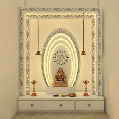 A modern home temple design featuring a backlit oval frame around a Ganesha idol, set within an intricately carved white border. This design includes built-in drawers for storage, blending functionality with divine aesthetics.