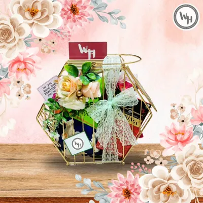 A beautiful example of a custom hamper in a unique gold-toned hexagonal wire basket. It's filled with premium teas and other goodies, adorned with delicate roses and a lace ribbon, perfect for a birthday or anniversary.