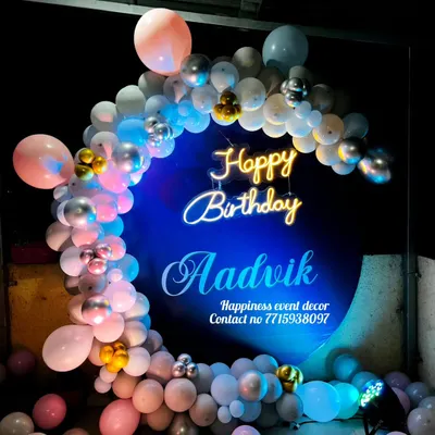 I also do birthday decorations, like this custom ring backdrop for Aadivk's birthday. The setup features a personalized neon sign with the name and a balloon garland in shades of blue, pink, and silver.